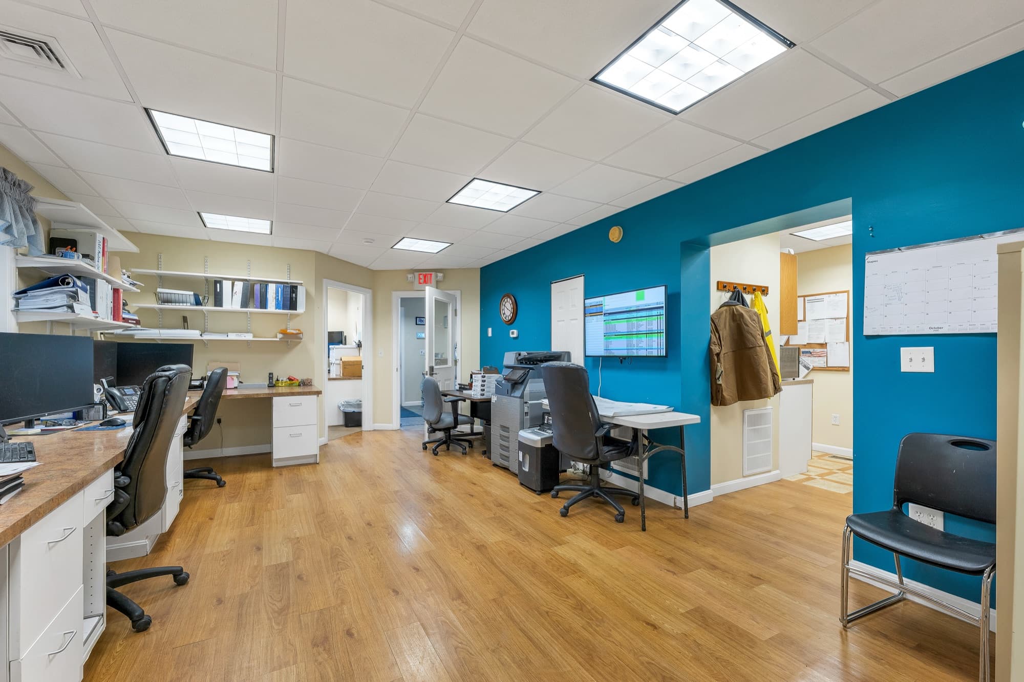 The open office looking toward a teal-walled office at the end