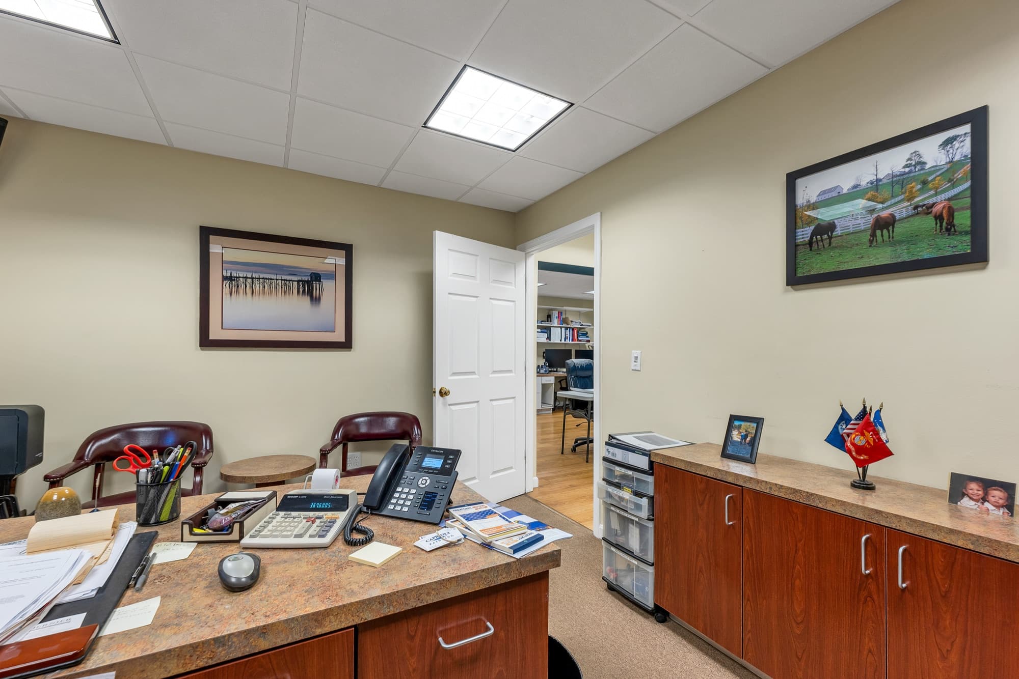 A private office with a desk, cherry cabinets, and a door to the open office