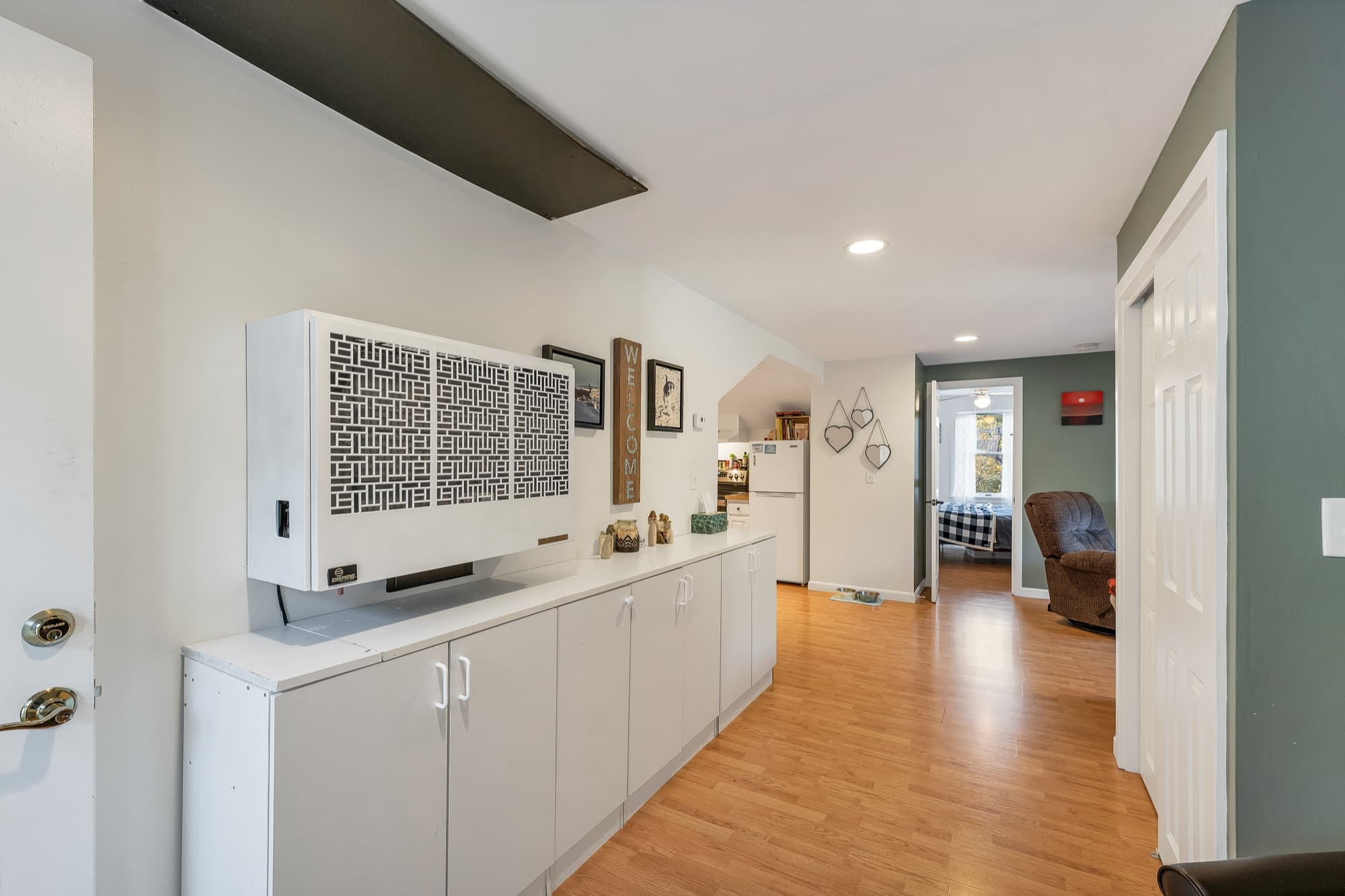 The 1-bedroom apartment's entry with cabinets and a Monitor heater on the wall, looking through to the kitchen