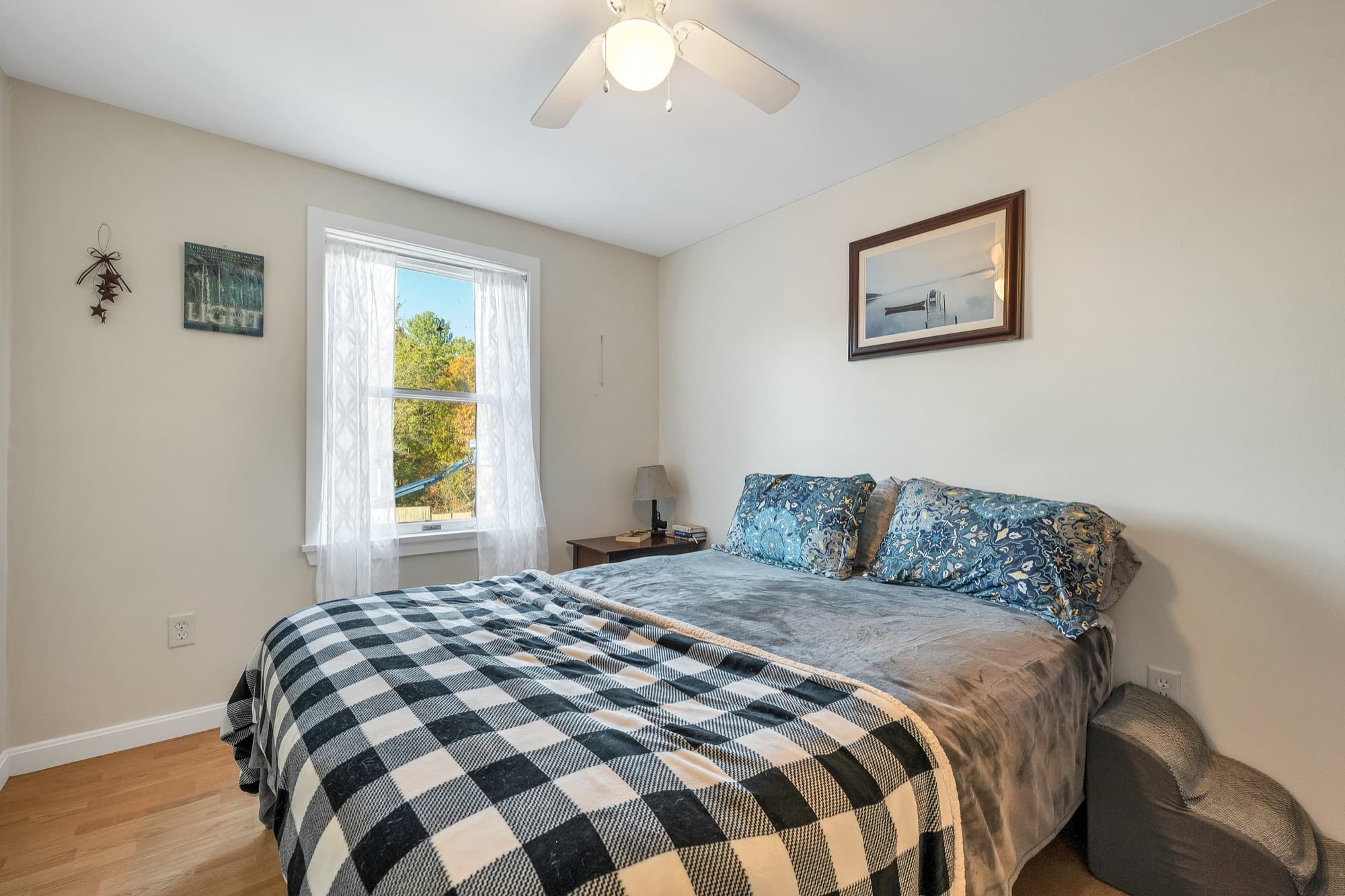 The 1-bedroom apartment's bedroom with a plaid comforter and 2 windows