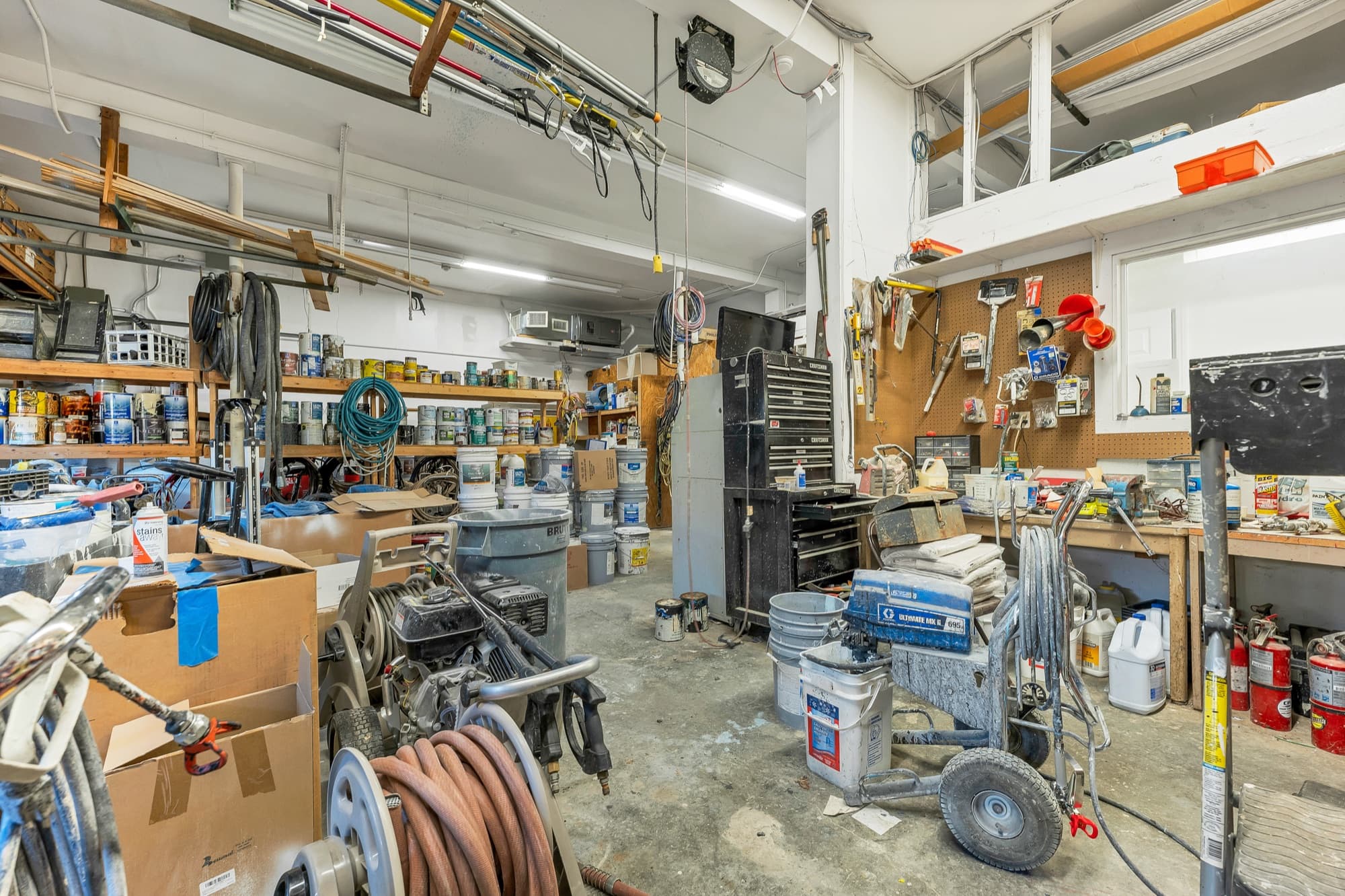 The workbench wall of the garage with pegboard and overhead racks