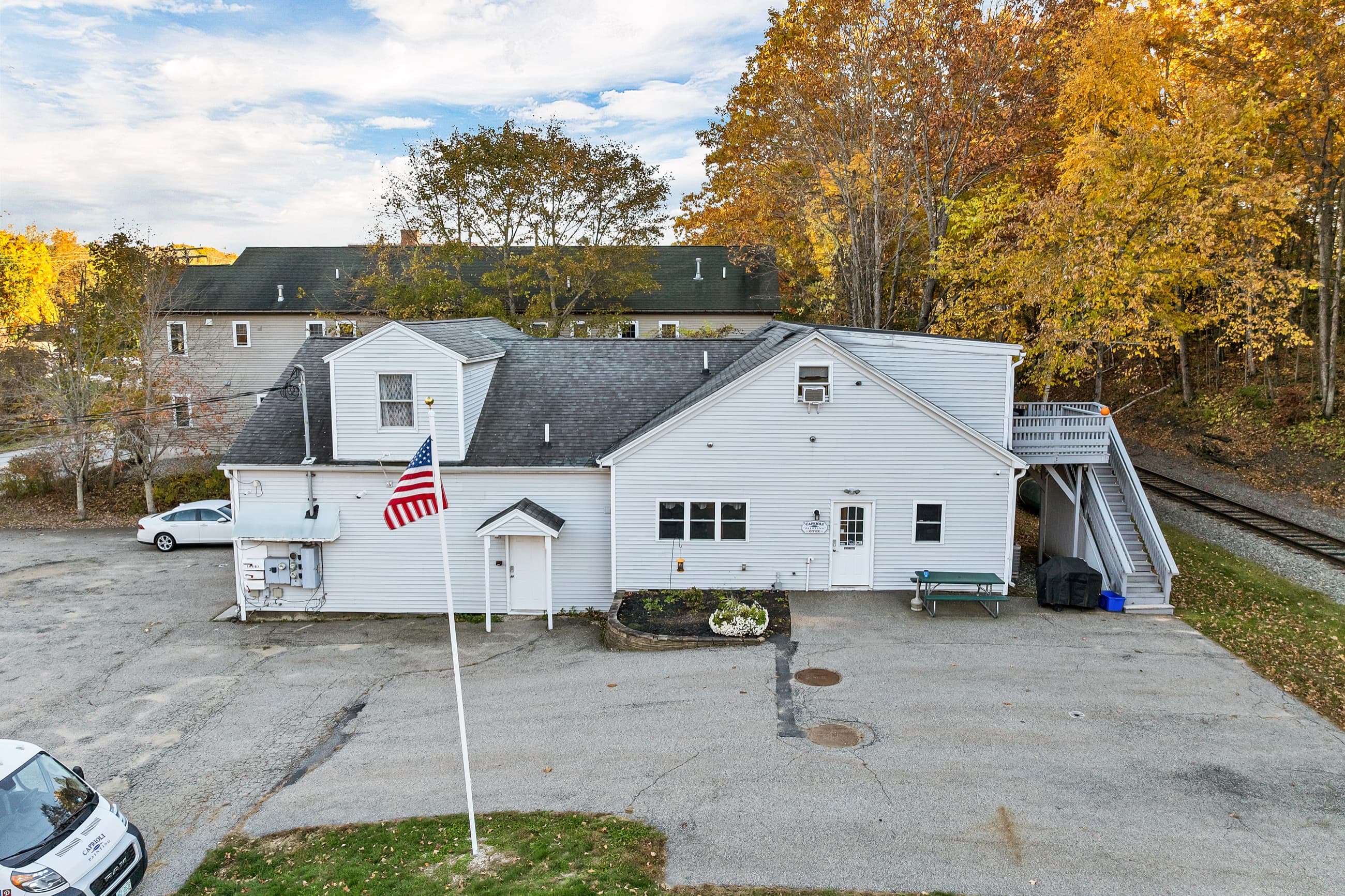 The office entry on the street side, with the flagpole and the front walk, the apartments above, and the exterior stair at the right